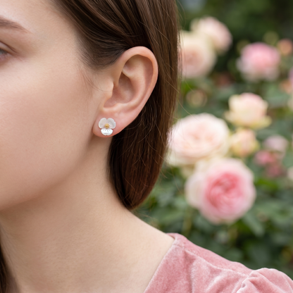 White flower stud earrings worn on model’s ear, gold-tone center visible