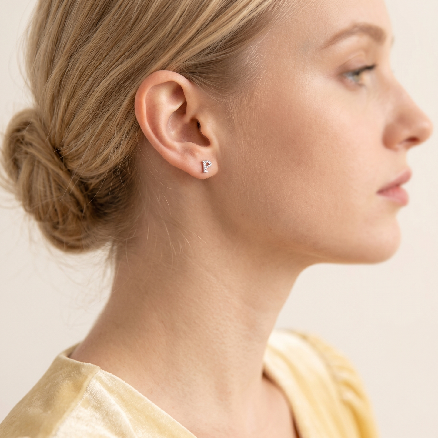 Paved initial stud earring rose-gold tone with rhinestone letter on the ear.