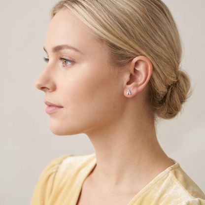 Paved initial stud earring letter A in silver-tone on the ear.