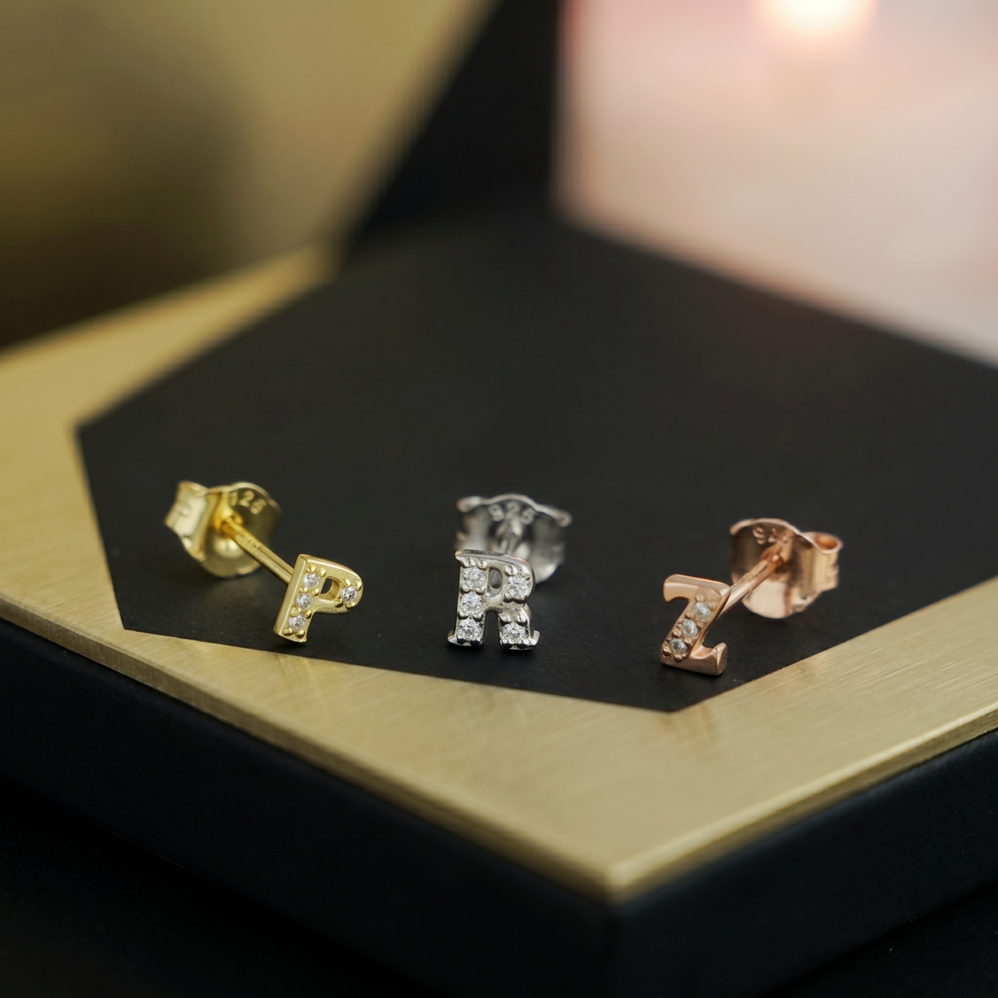 Paved initial stud earrings with three letters: gold-tone, silver-tone, and rose-gold.