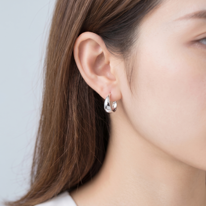 Wide Dome Huggie Earrings on ear, polished silver domed hoop profile