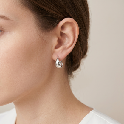 Wide Dome Huggie Earrings worn close-up, silver-tone domed hoop on ear