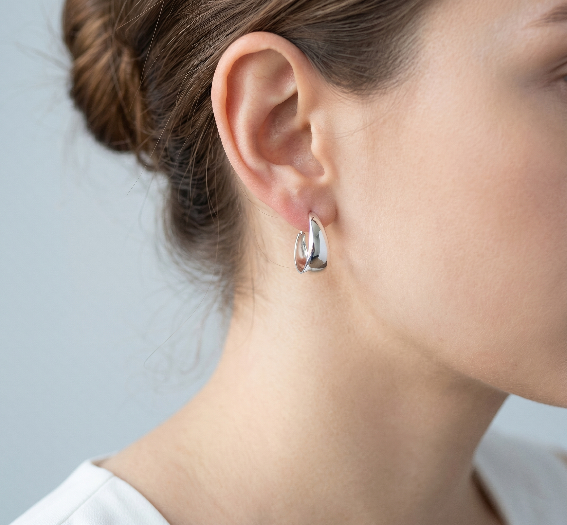 Wide Dome Huggie Earrings worn, thick silver-tone oval hoop with post-back