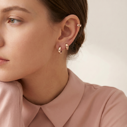 Gold-tone bold huggie hoop earrings on ear, stacked pair