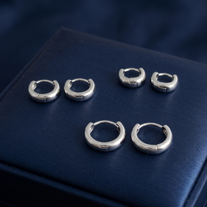Rhodium-plated sleeper huggie earrings on blue display base