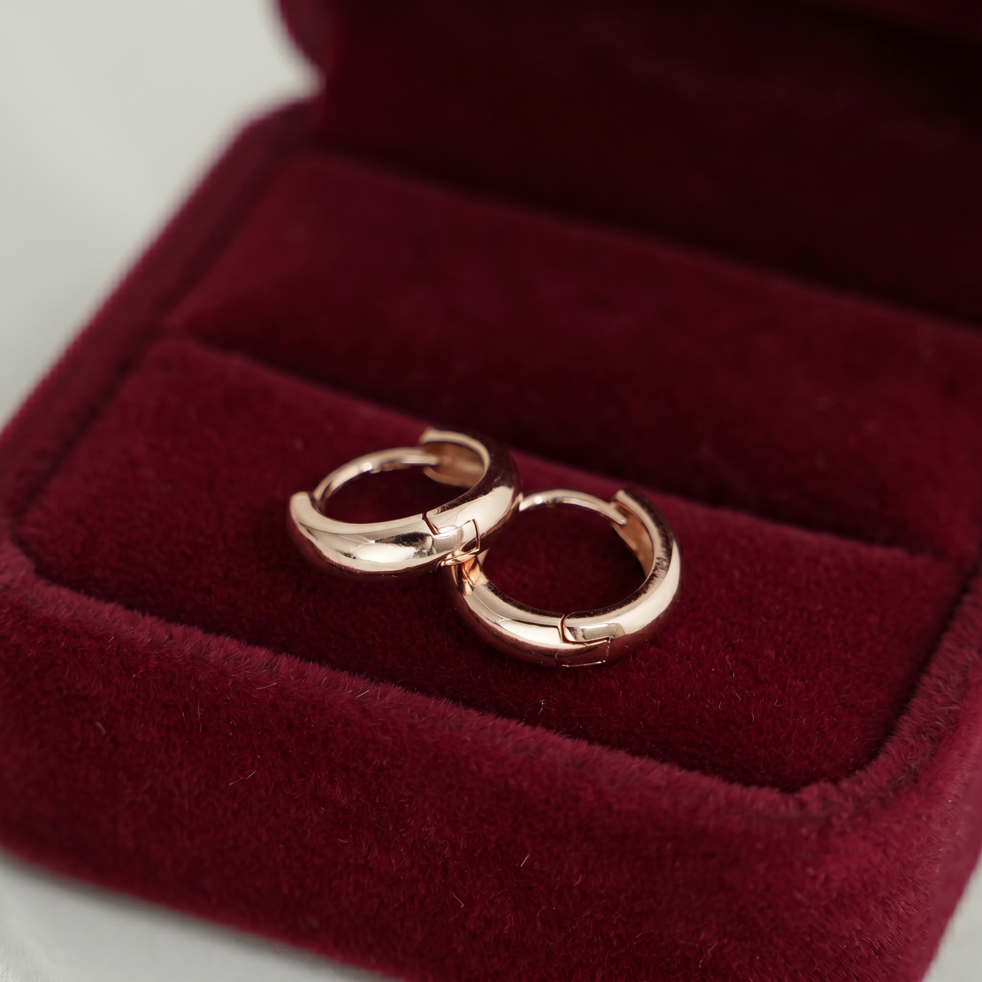 Rose gold sleeper huggie earrings in red velvet jewelry box