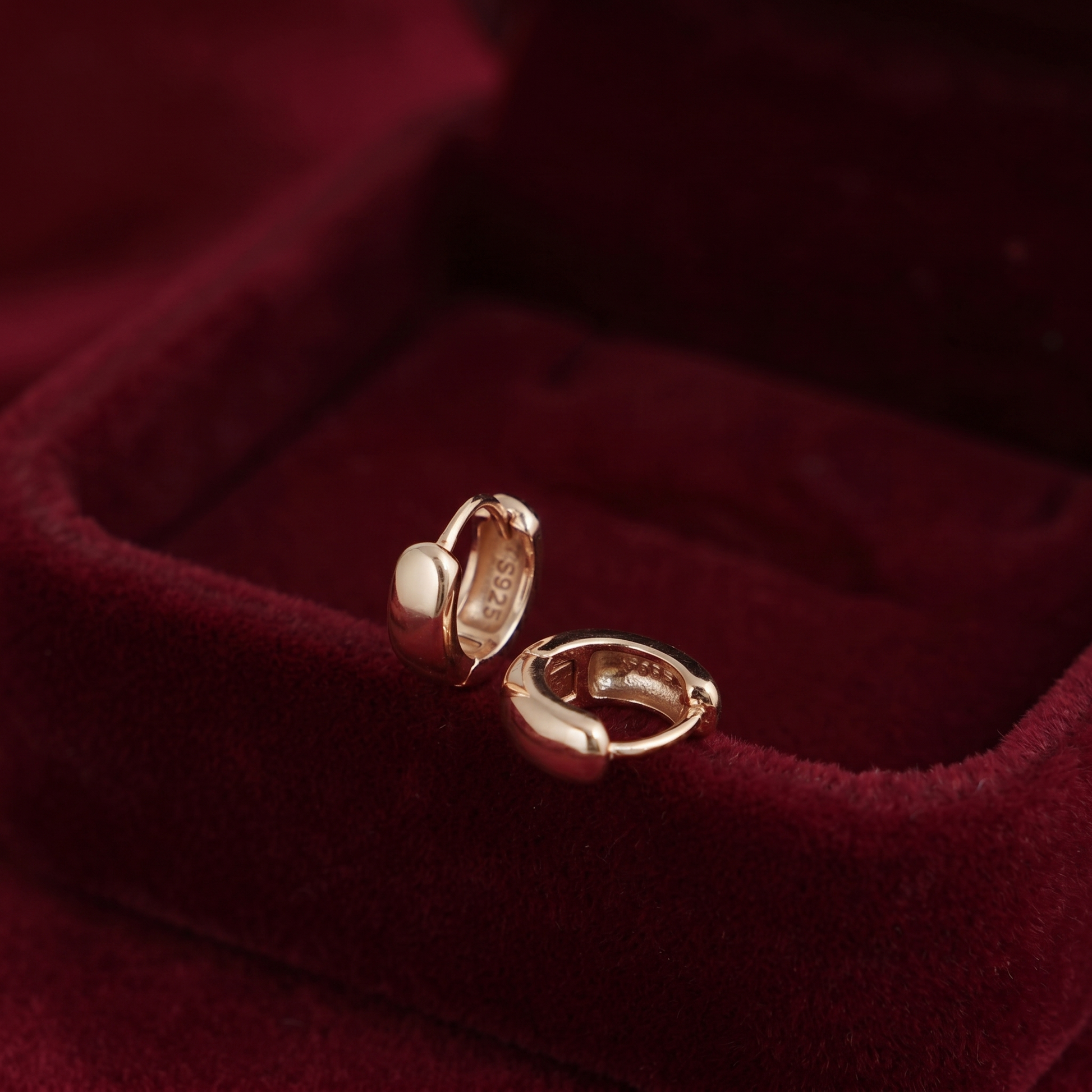 Gold sleeper huggie earrings in red velvet jewelry box