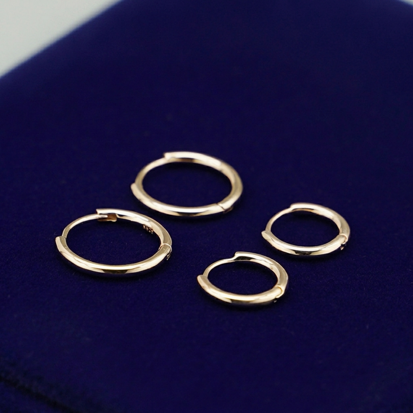 Gold-tone huggie hoop earrings with hinged closure, several pairs arranged