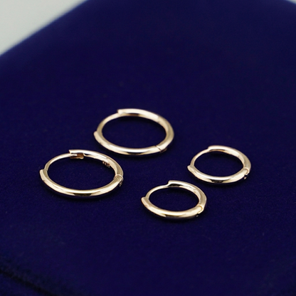 Gold-tone huggie hoop earrings with hinged closure, several pairs arranged