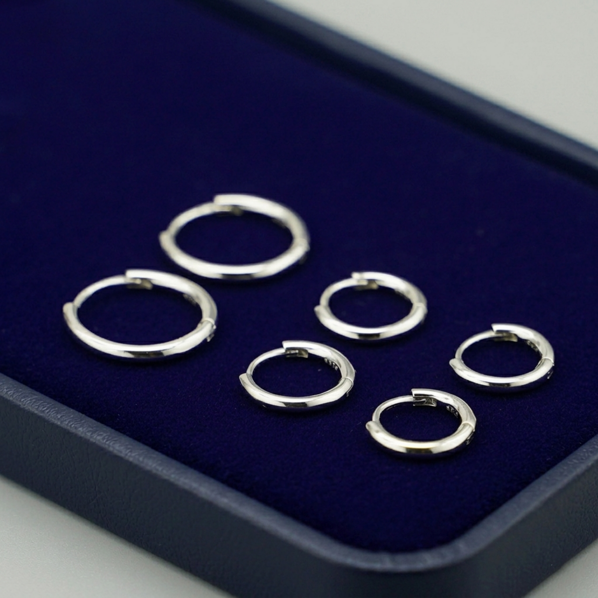 Rhodium-tone huggie hoop earrings with hinged closure, several pairs arranged