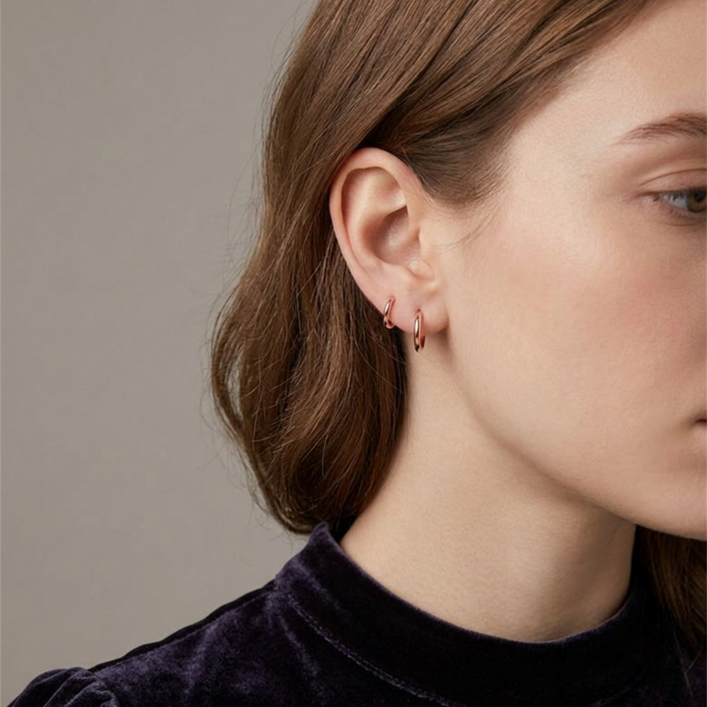 Gold-tone huggie hoop earrings on ear, small hoop stack