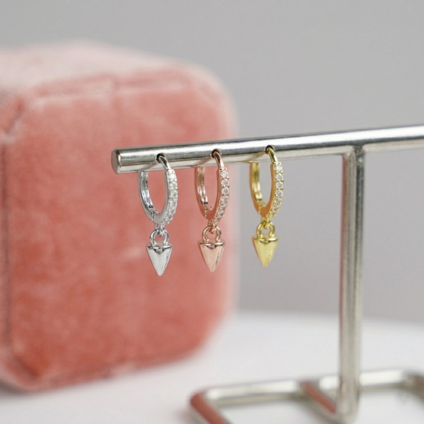 Cone-spike hoop earrings on display: silver, rose gold, and gold with pointed charms