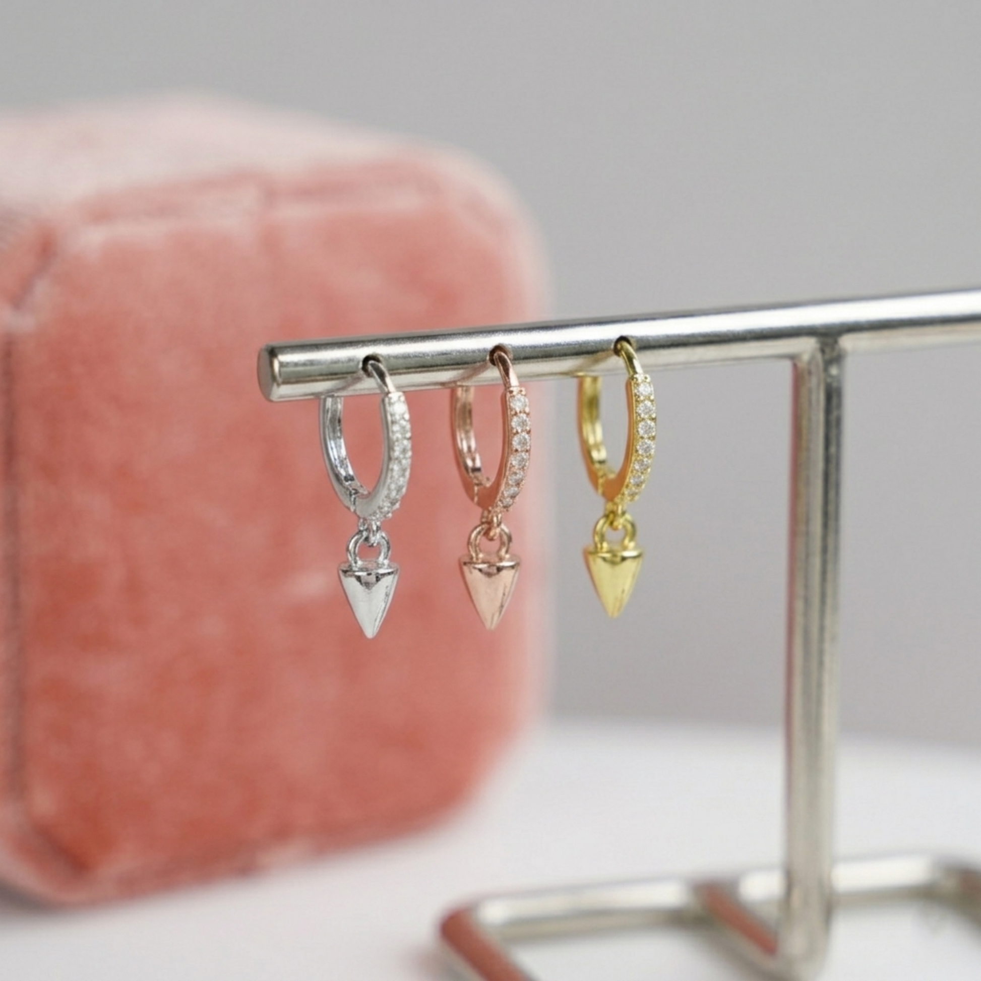 Cone-spike hoop earrings on display: silver, rose gold, and gold with pointed charms