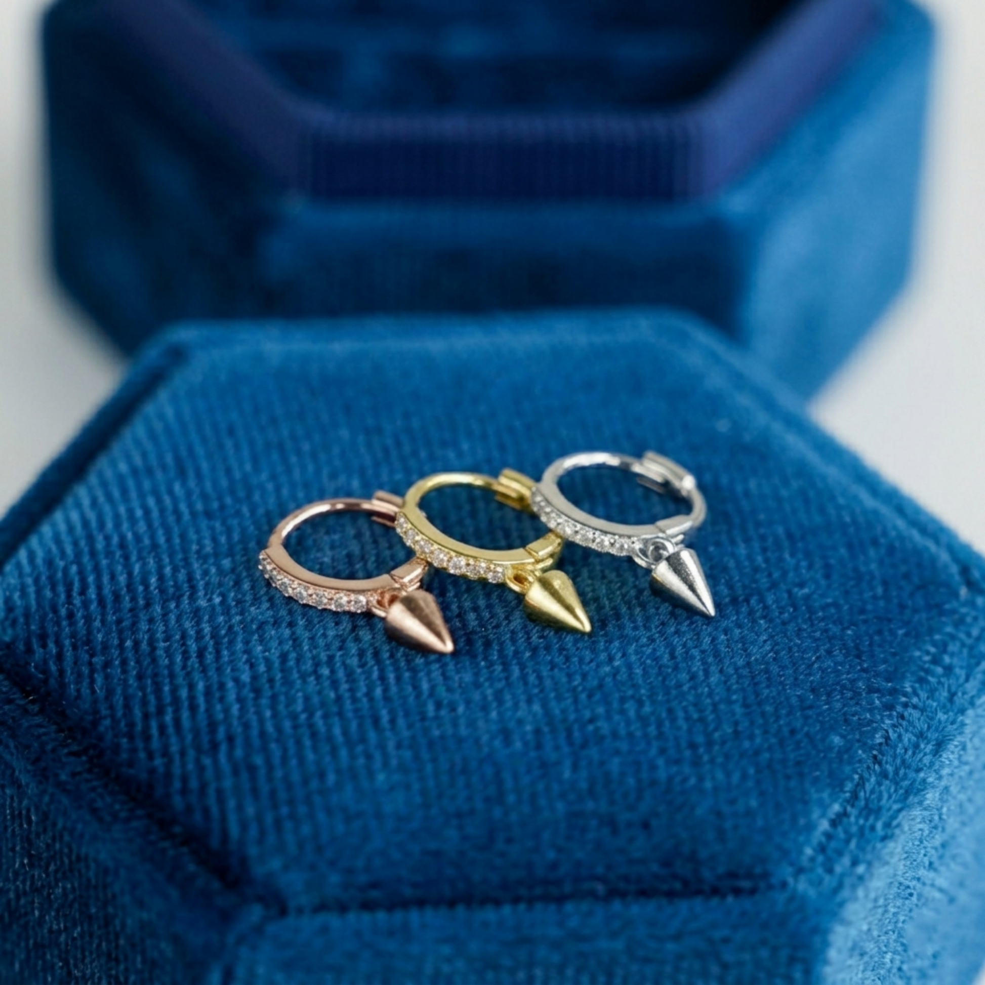 Cone-spike hoop earrings in mixed metals, each with a small pointed charm