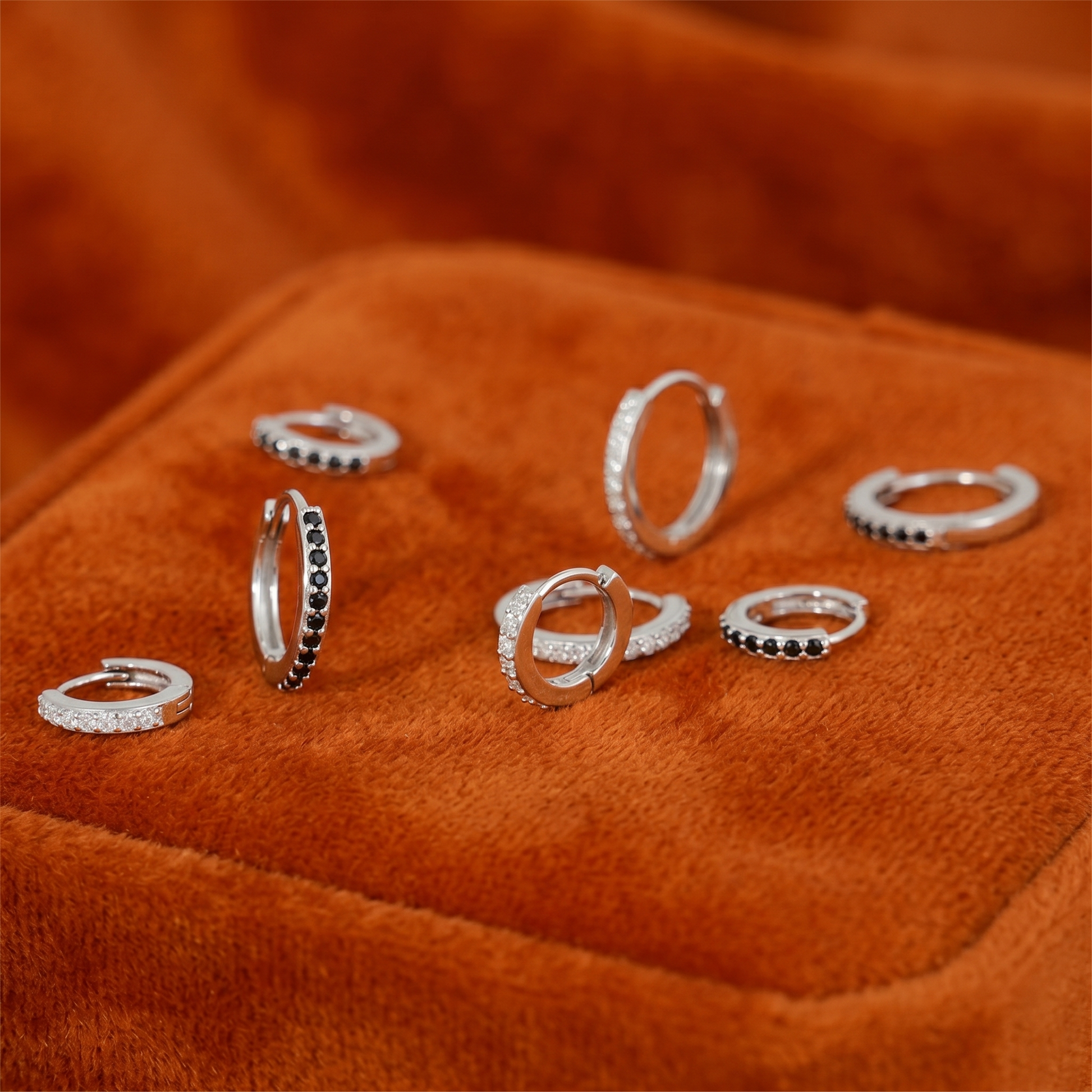 Mix of huggie hoop earrings: silver-tone with clear and dark stone rows