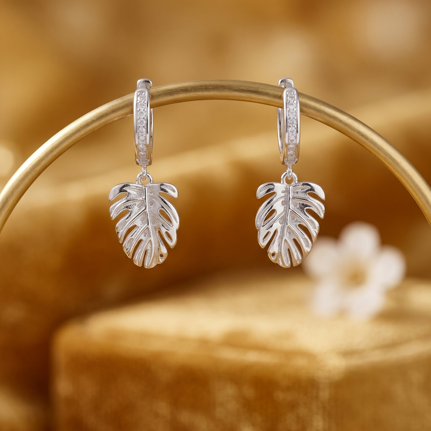 Monstera Leaf Drop Huggies on display: hinged silver hoops with Monstera leaf charms