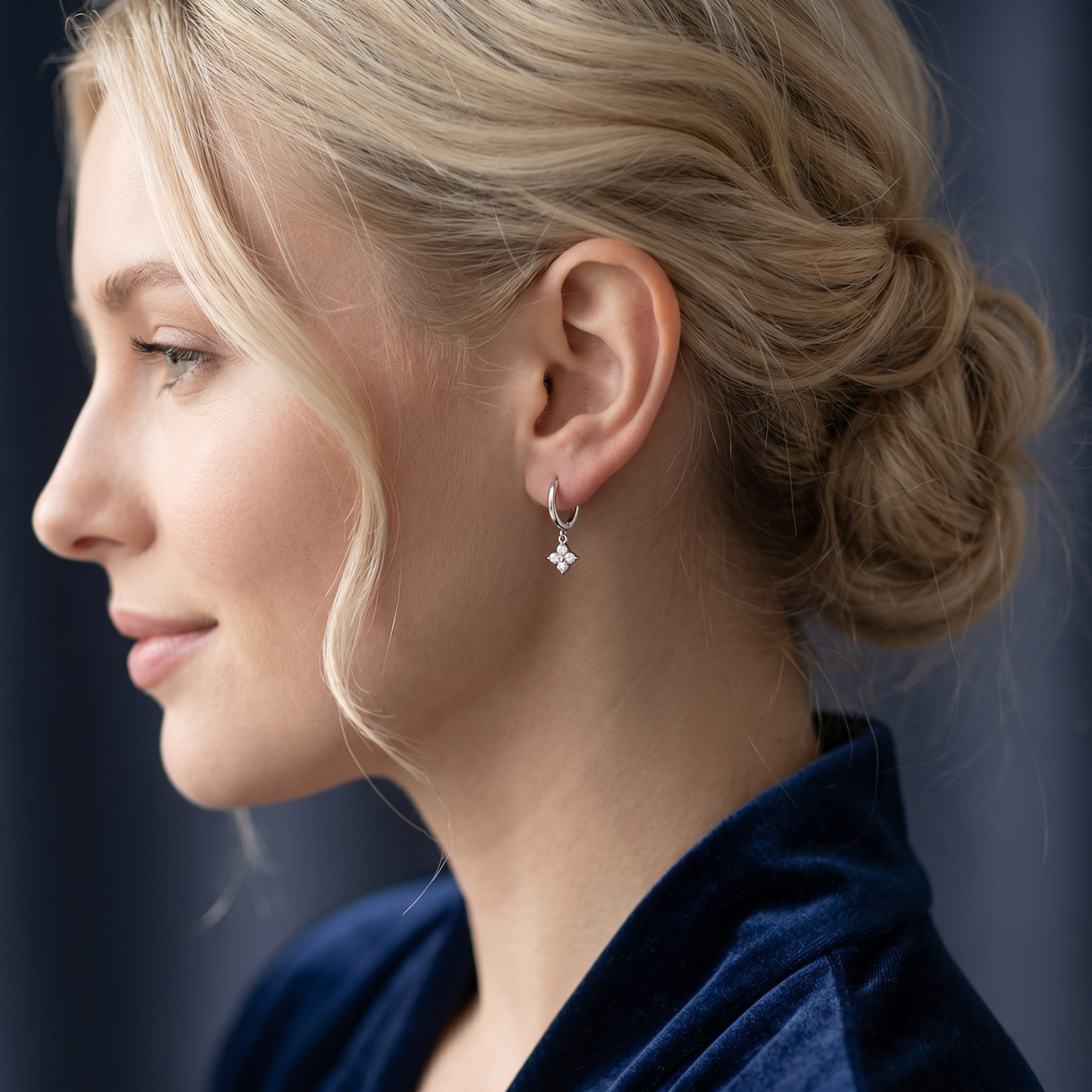 Gold flower charm huggie earrings on model, four-petal crystal charm