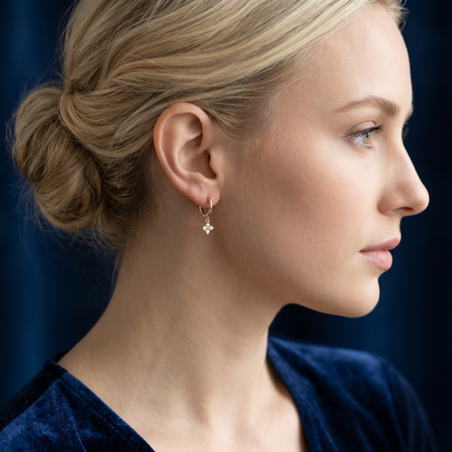 Gold flower charm huggie earrings on model, small crystal cluster