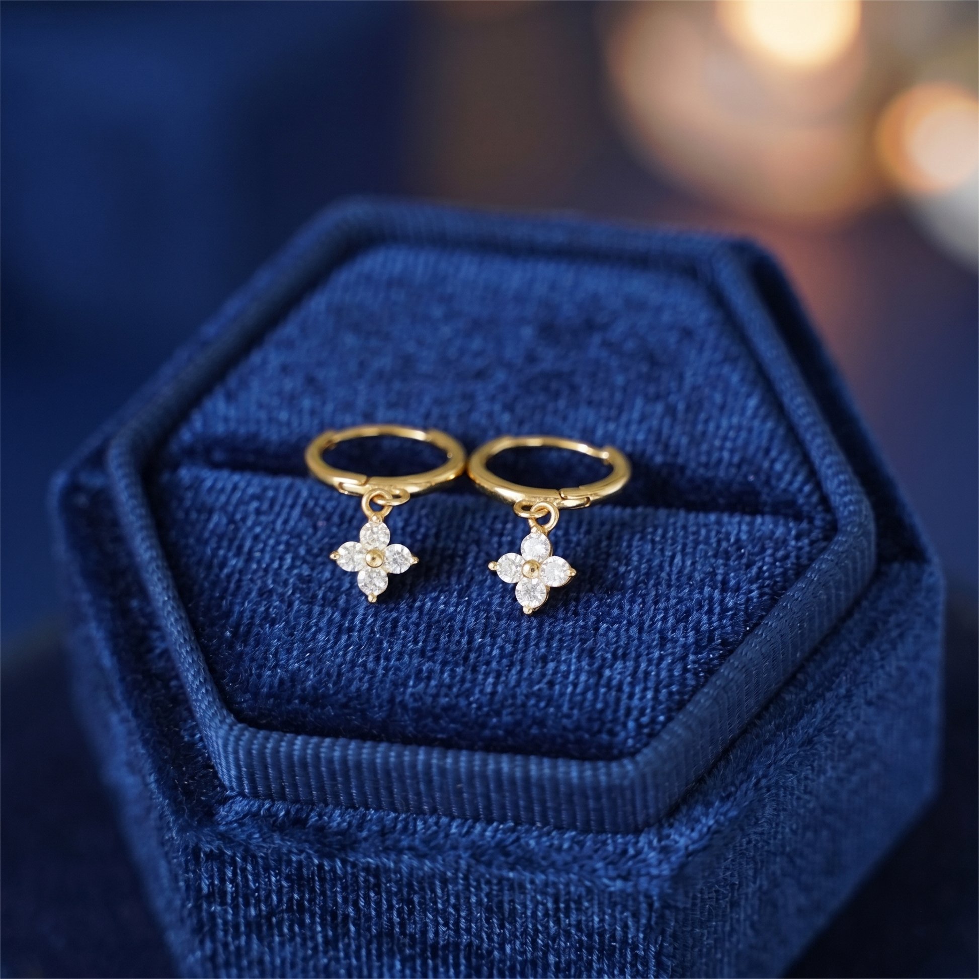 Gold huggie hoop earrings with four-petal flower charm and small crystal drops
