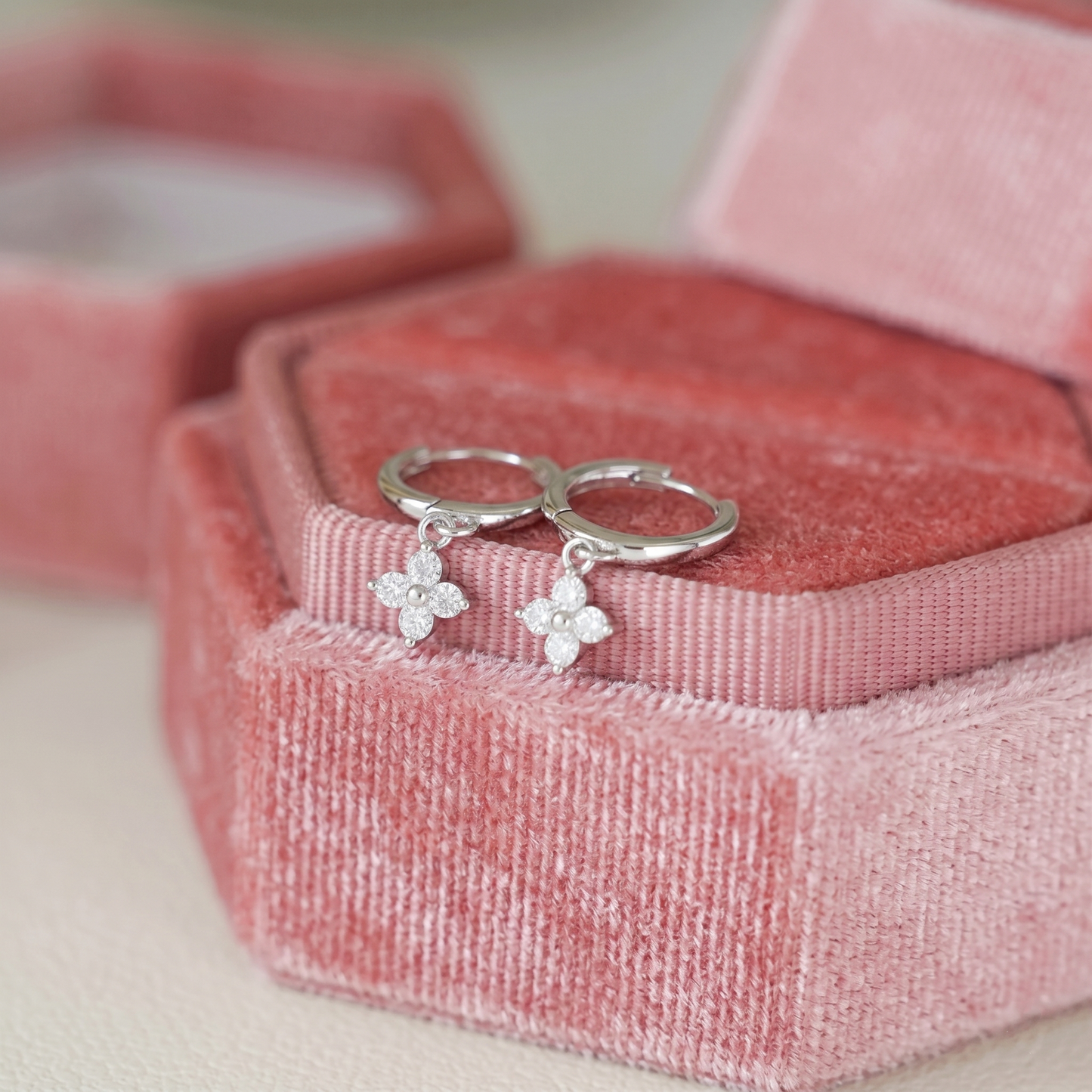Silver huggie hoop earrings with four-petal flower charm and small crystals
