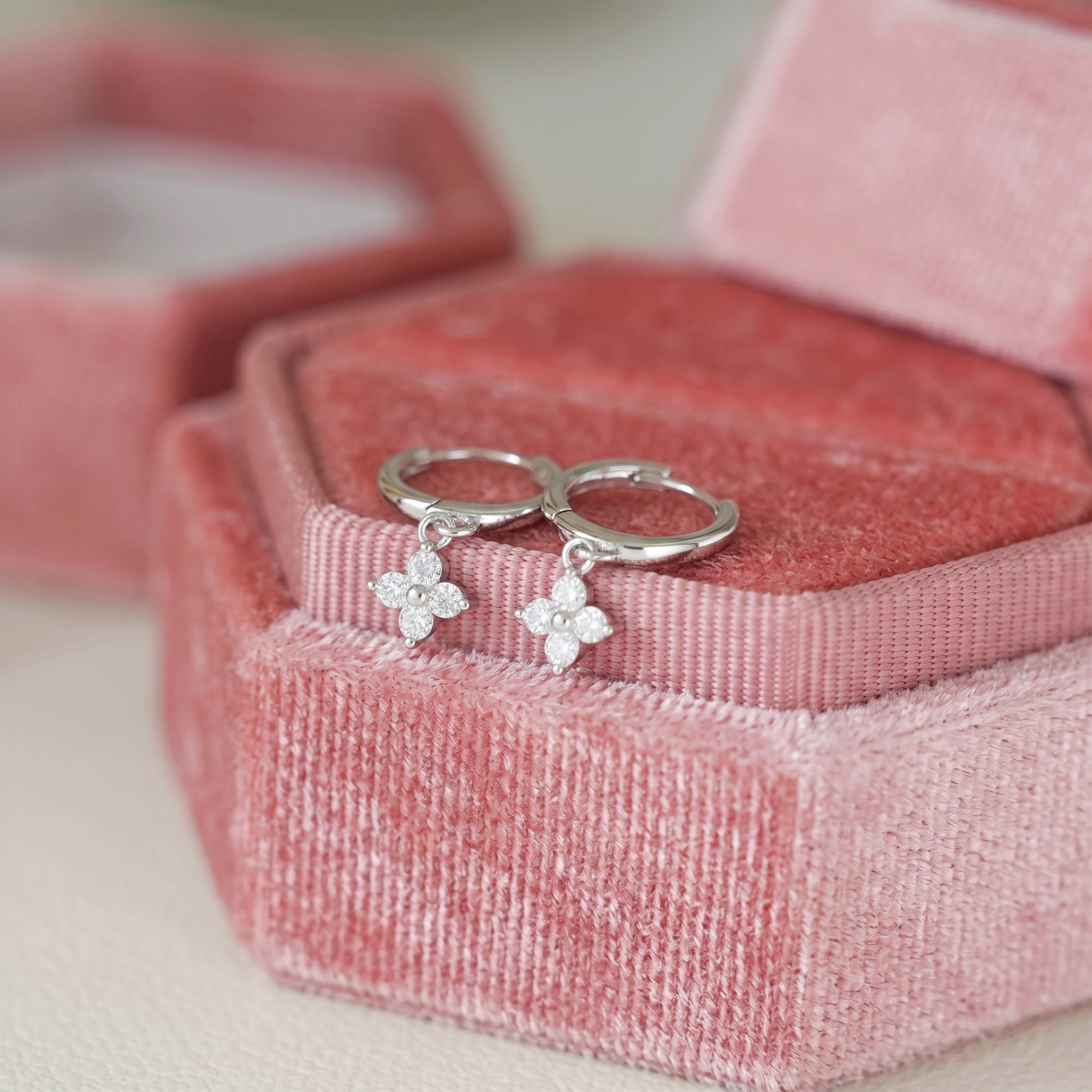 Silver huggie hoop earrings with four-petal flower charm and small crystals