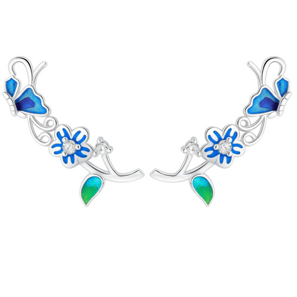 Silver-tone butterfly climber earrings with blue enamel petals and green teardrop accents