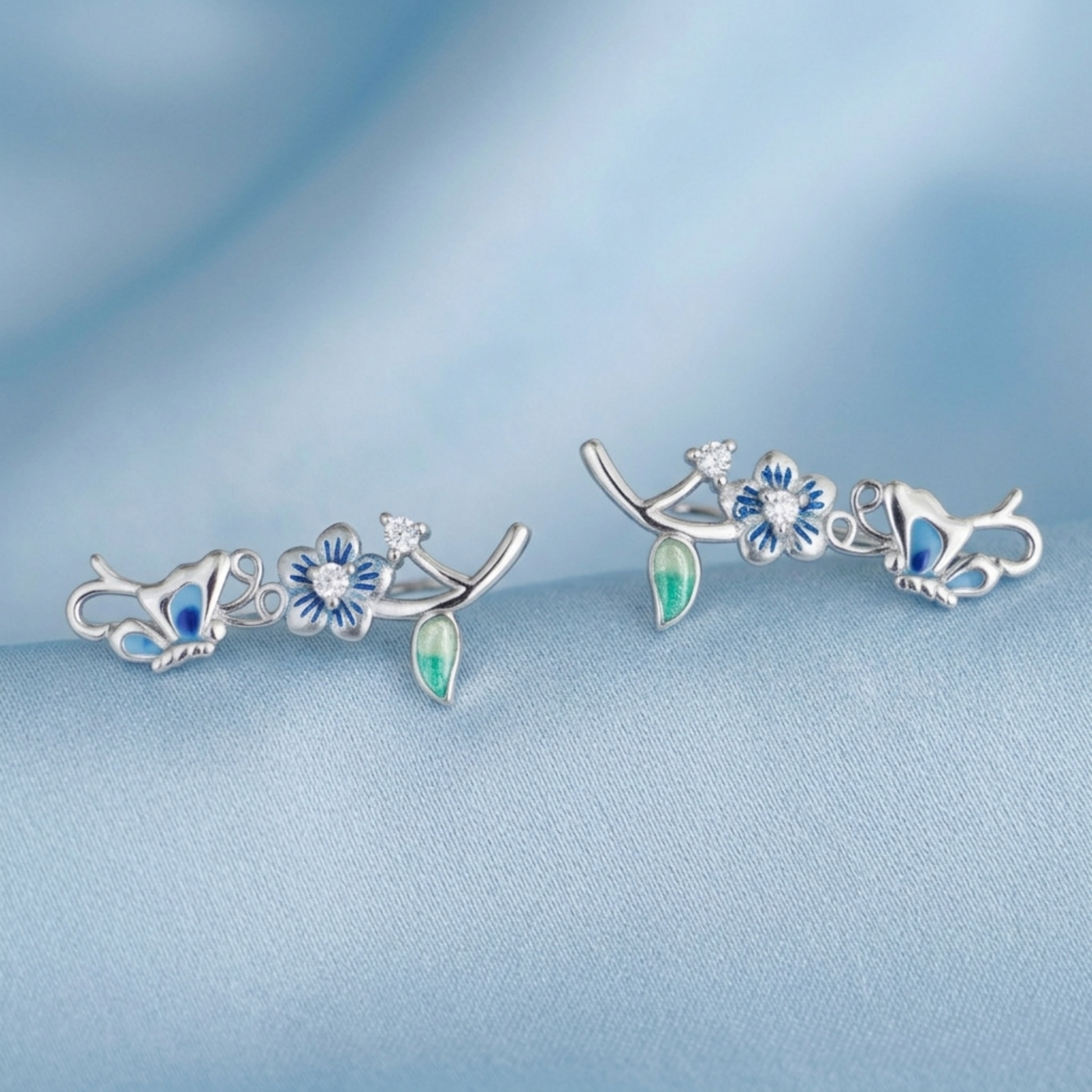 Silver butterfly climber earrings with blue enamel flowers and green teardrop accents