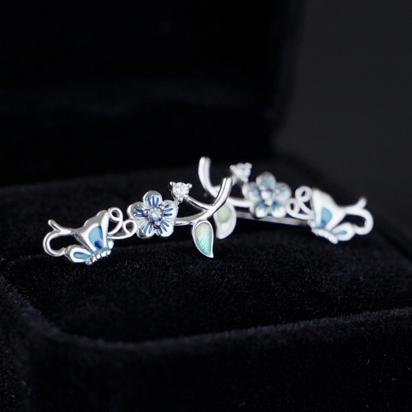 Silver butterfly climber earrings with blue enamel wings and green teardrop stones