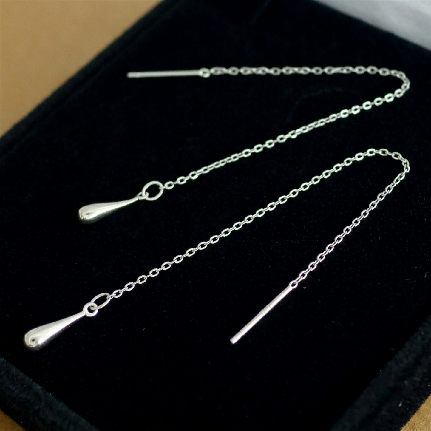 Silver-tone teardrop threader earrings with long chain and teardrop drops on pouch