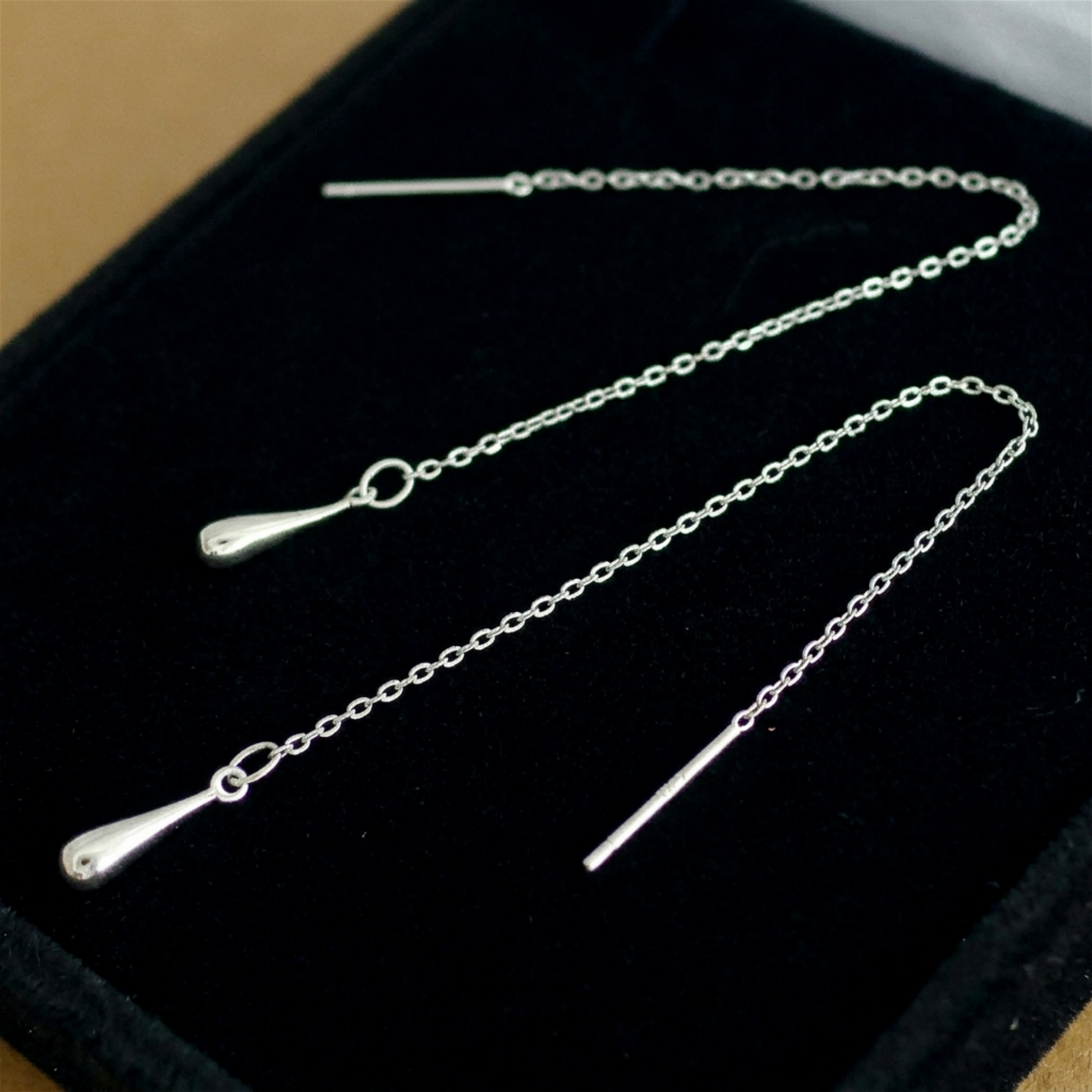 Silver-tone teardrop threader earrings with long chain and teardrop drops on pouch