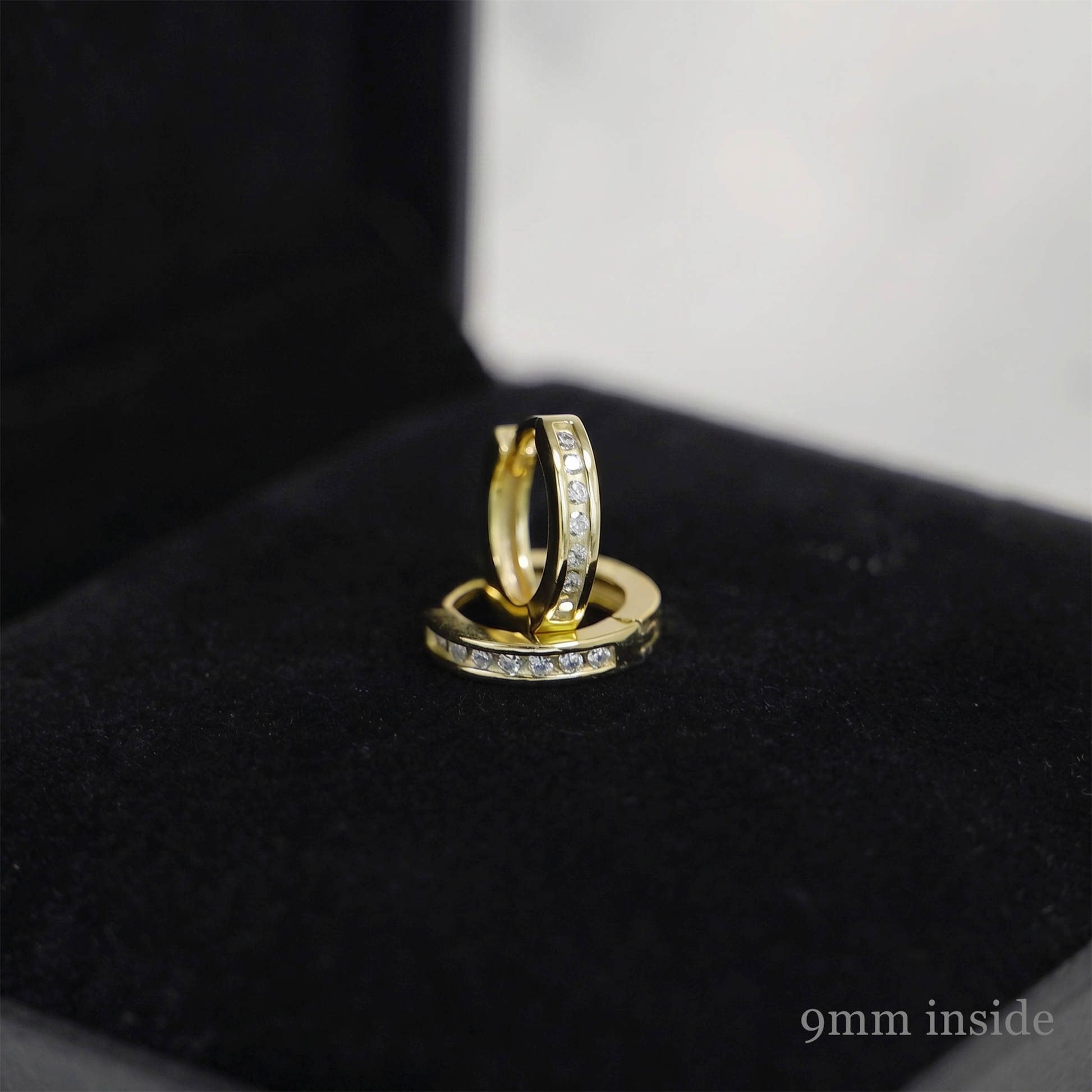 Gold huggie hoop earrings with stone row, inner edge visible