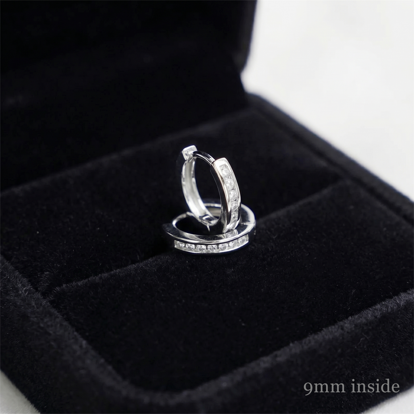 Rhodium huggie hoop earrings with a row of inset stones, side view