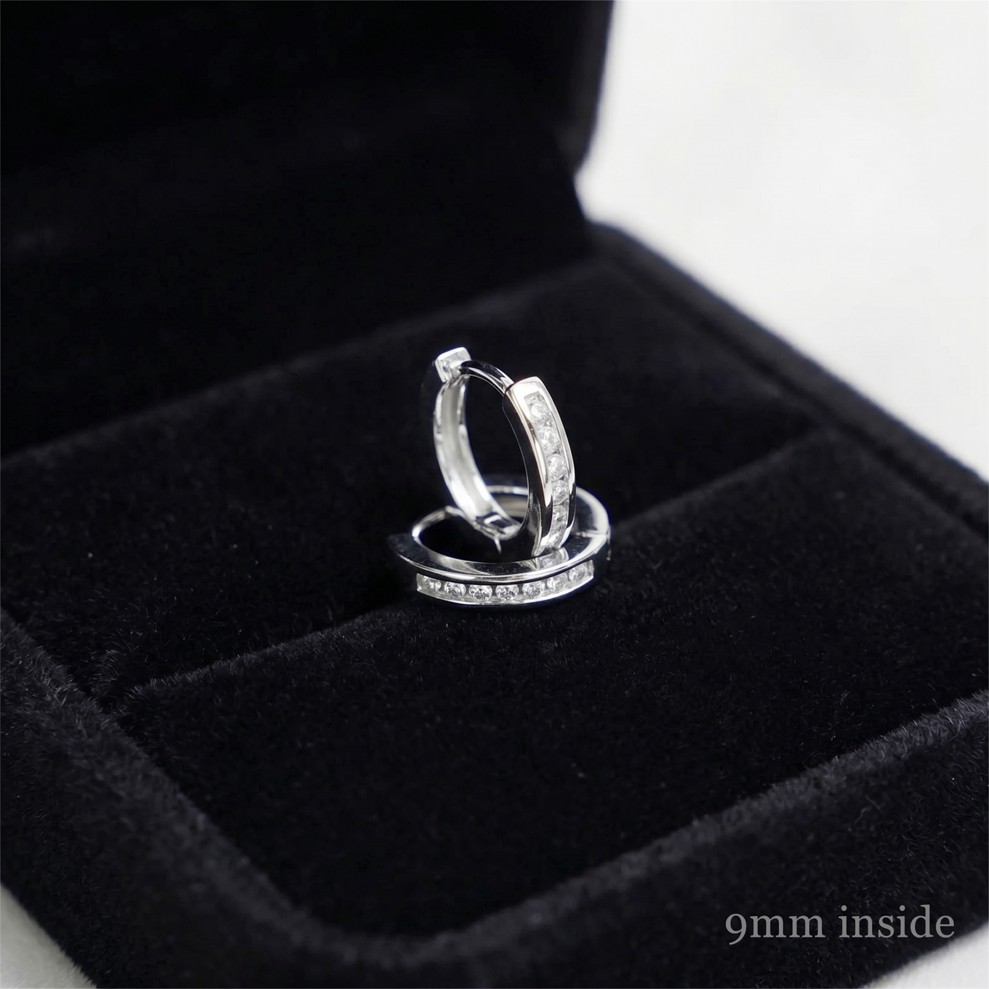 Rhodium huggie hoop earrings with a row of inset stones, side view