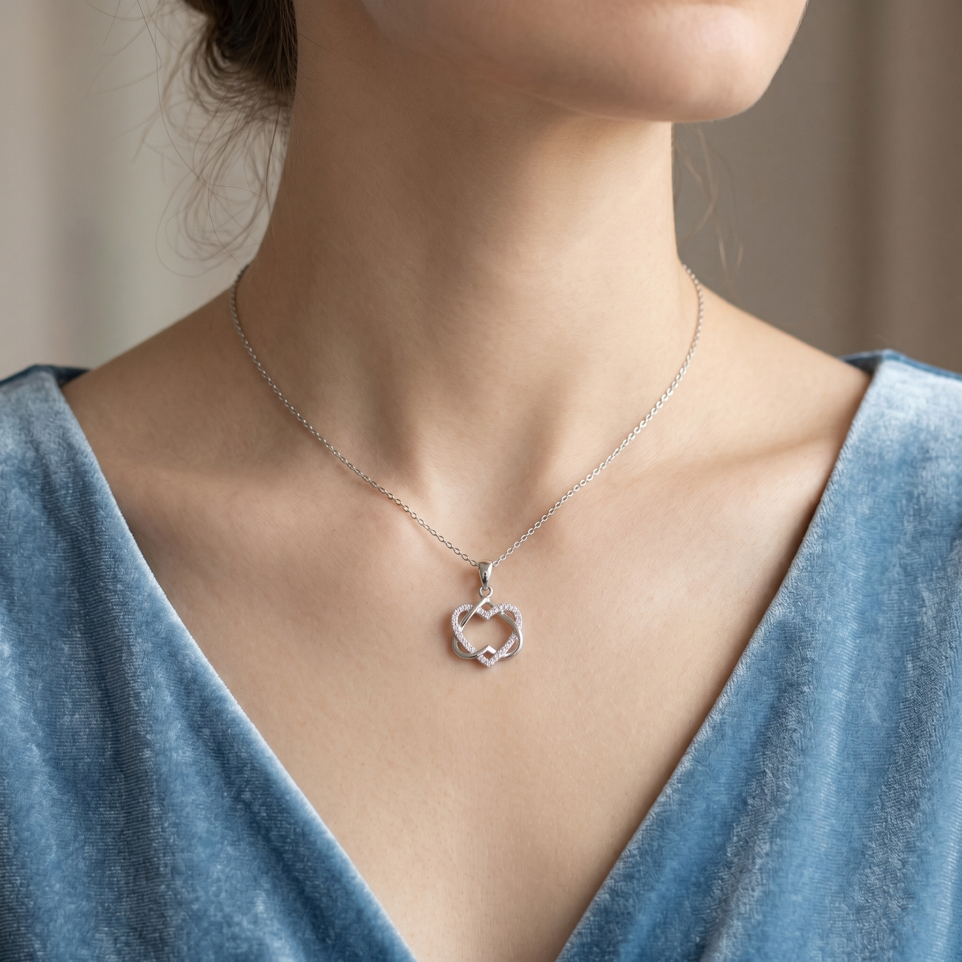 Silver heart knot pendant necklace worn on a neckline