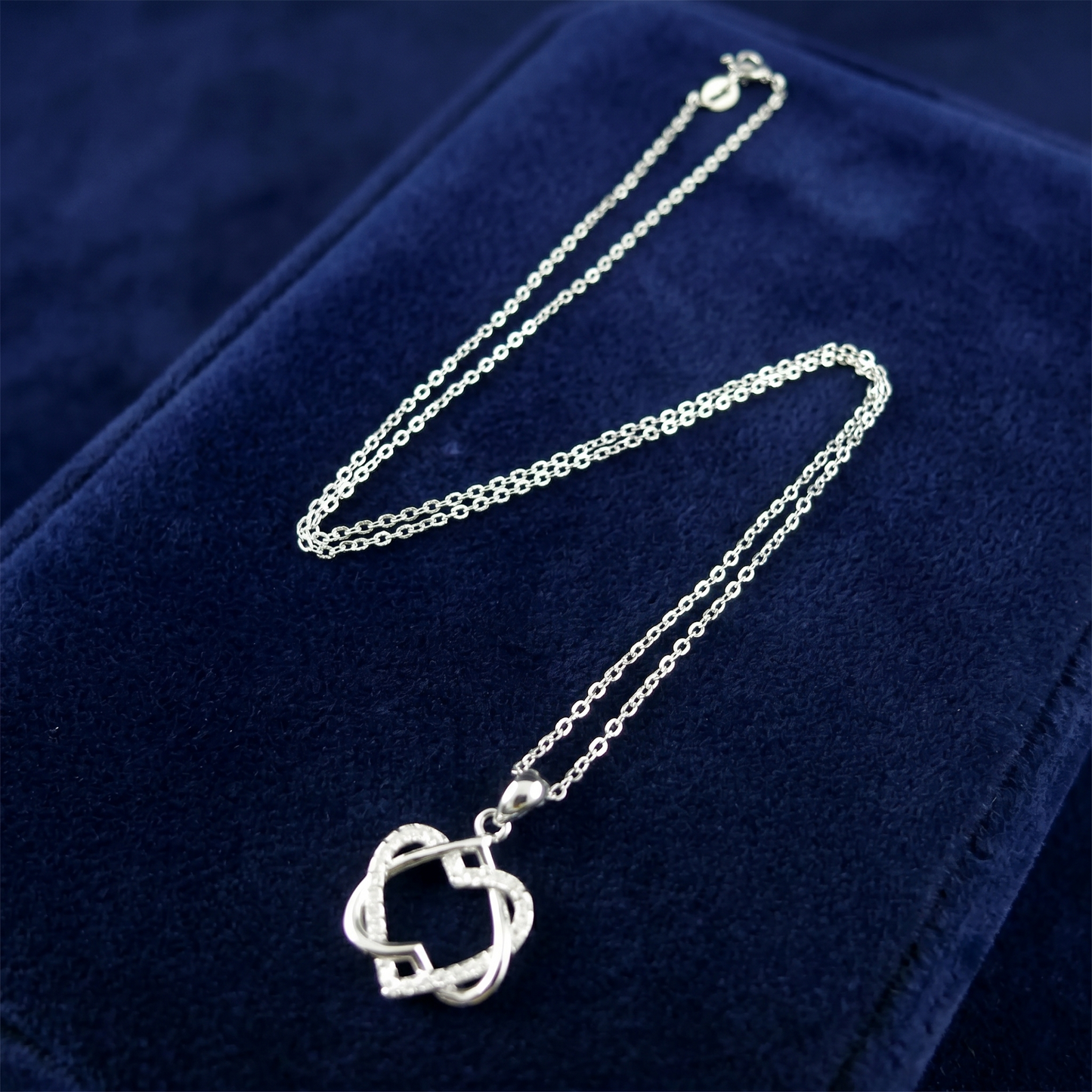 Silver heart knot pendant necklace laid flat with chain