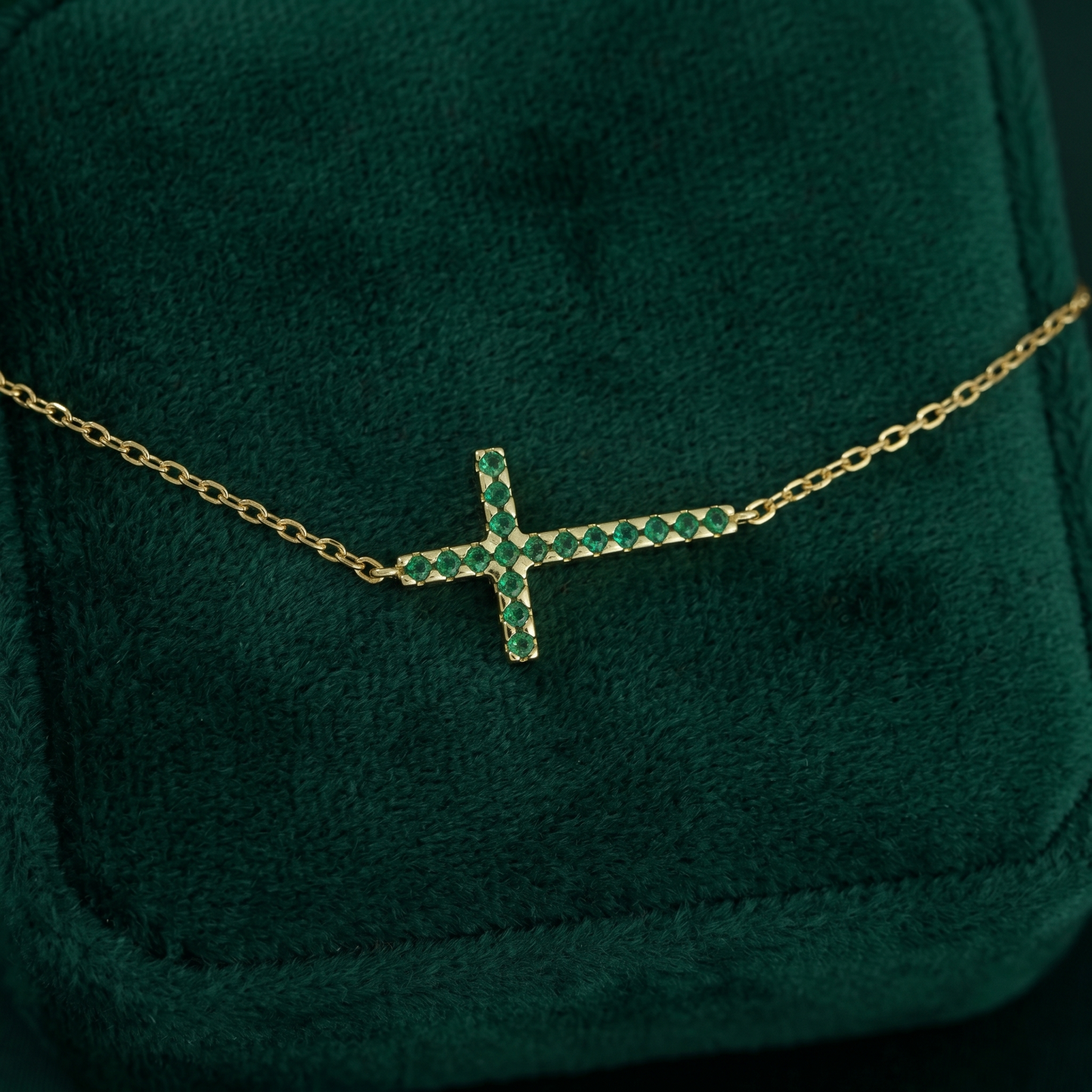 Gold-tone cross CZ necklace with green crystal stones and fine chain, close-up