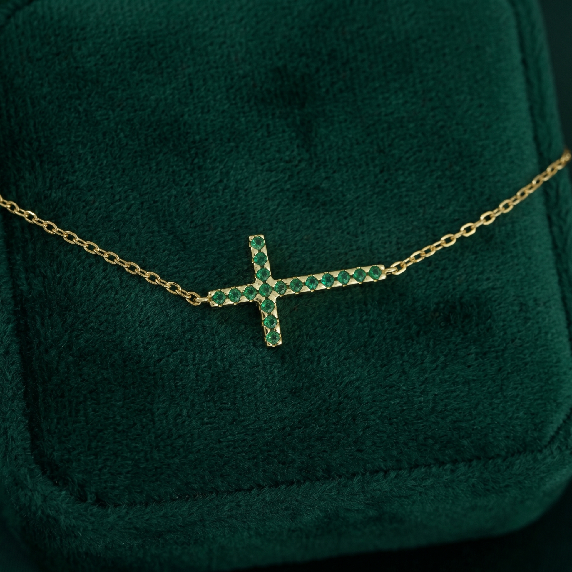 Gold-tone cross CZ necklace with green crystal stones and fine chain, close-up