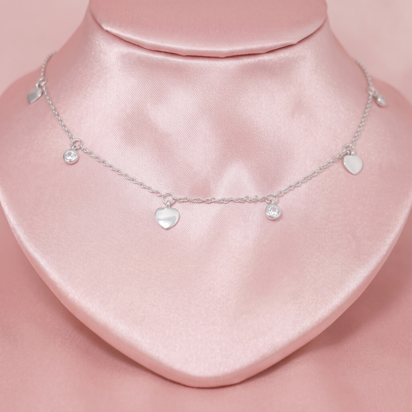 Silver-tone choker with three heart charms and two small round CZ charms