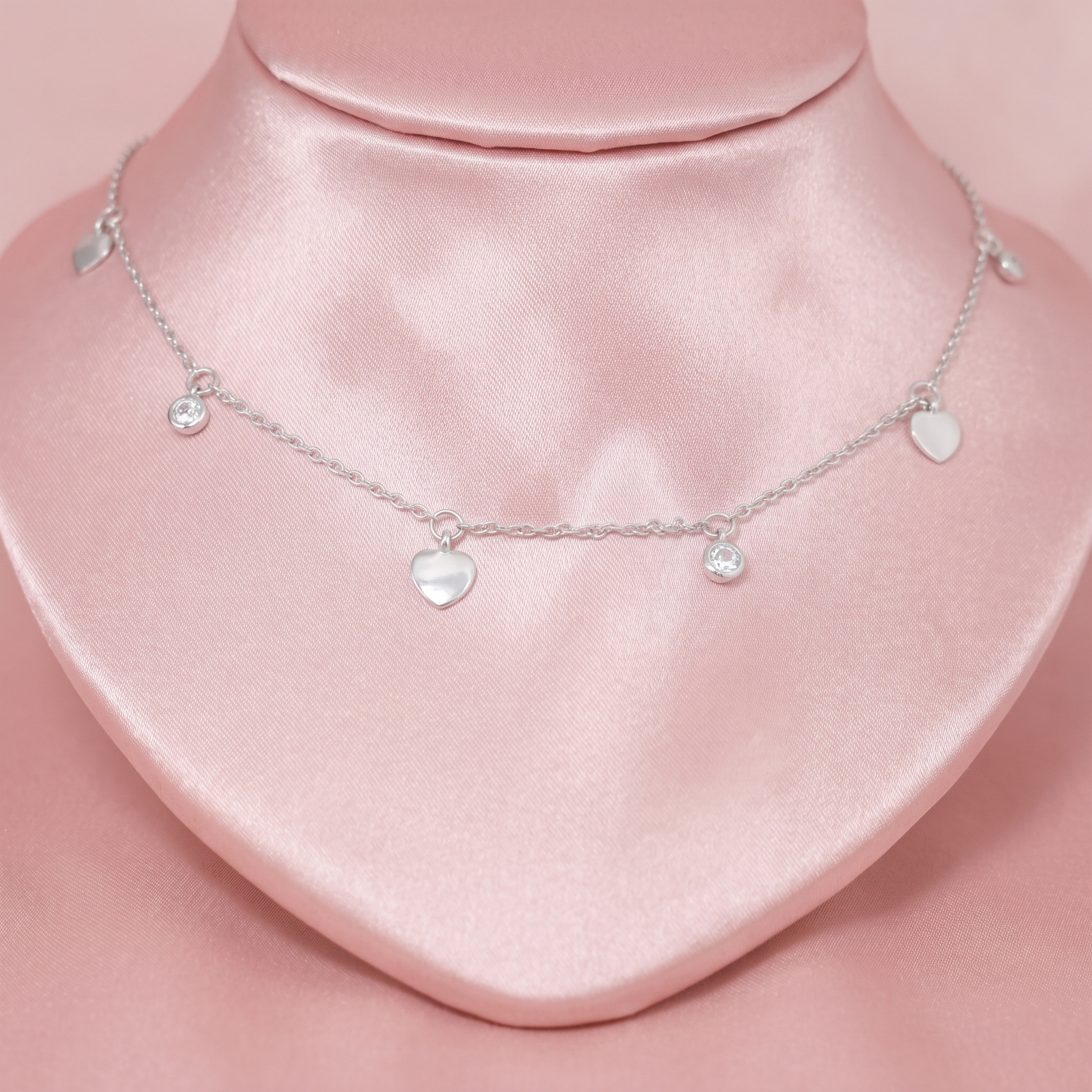 Silver-tone choker with three heart charms and two small round CZ charms