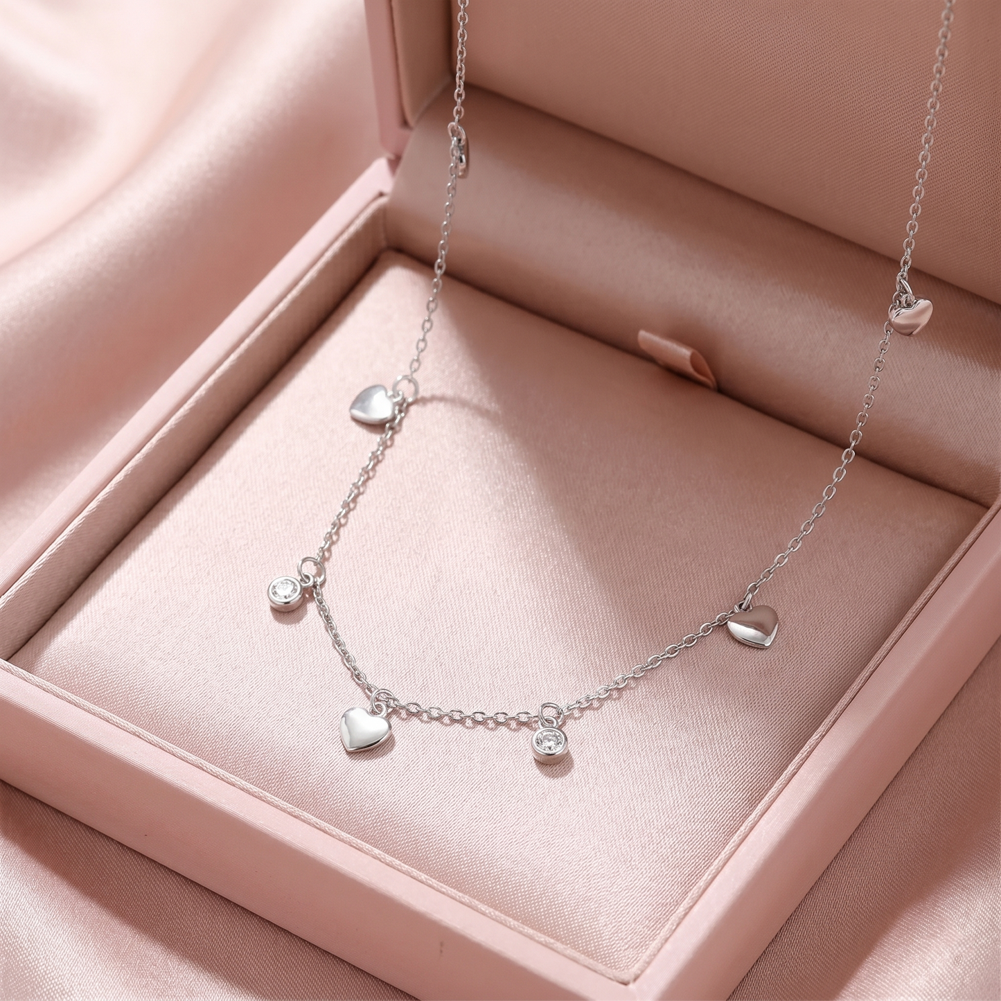 Silver-tone heart choker with small round CZ discs and three dangling heart charms