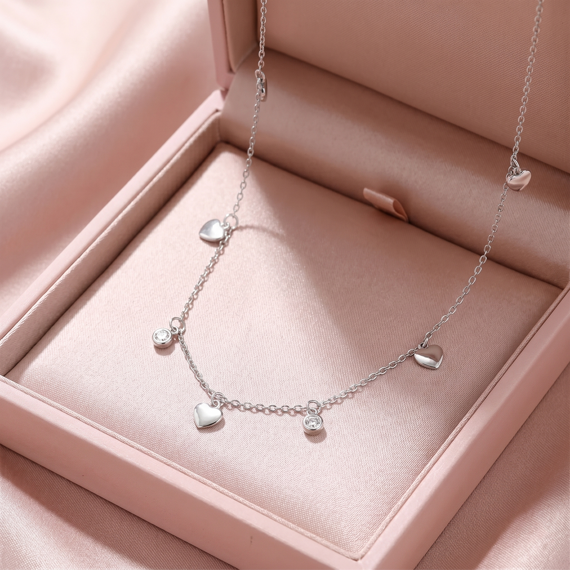 Silver-tone heart choker with small round CZ discs and three dangling heart charms