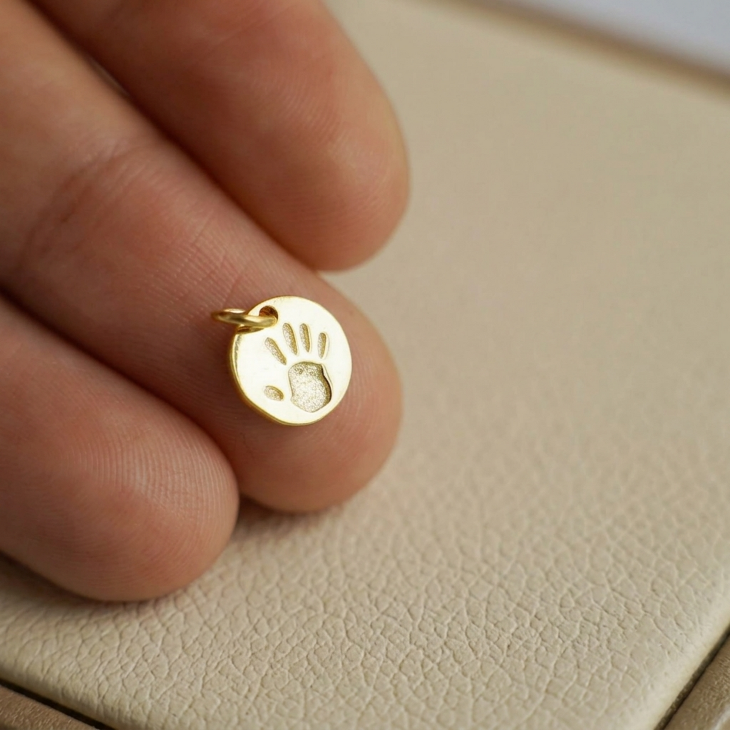 Small round gold charm with handprint design and bail loop