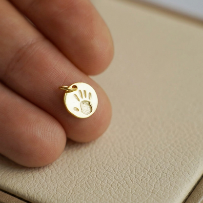 Small round gold charm with handprint design and bail loop