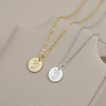Layered charm necklaces with round handprint and footprint pendants in gold and silver