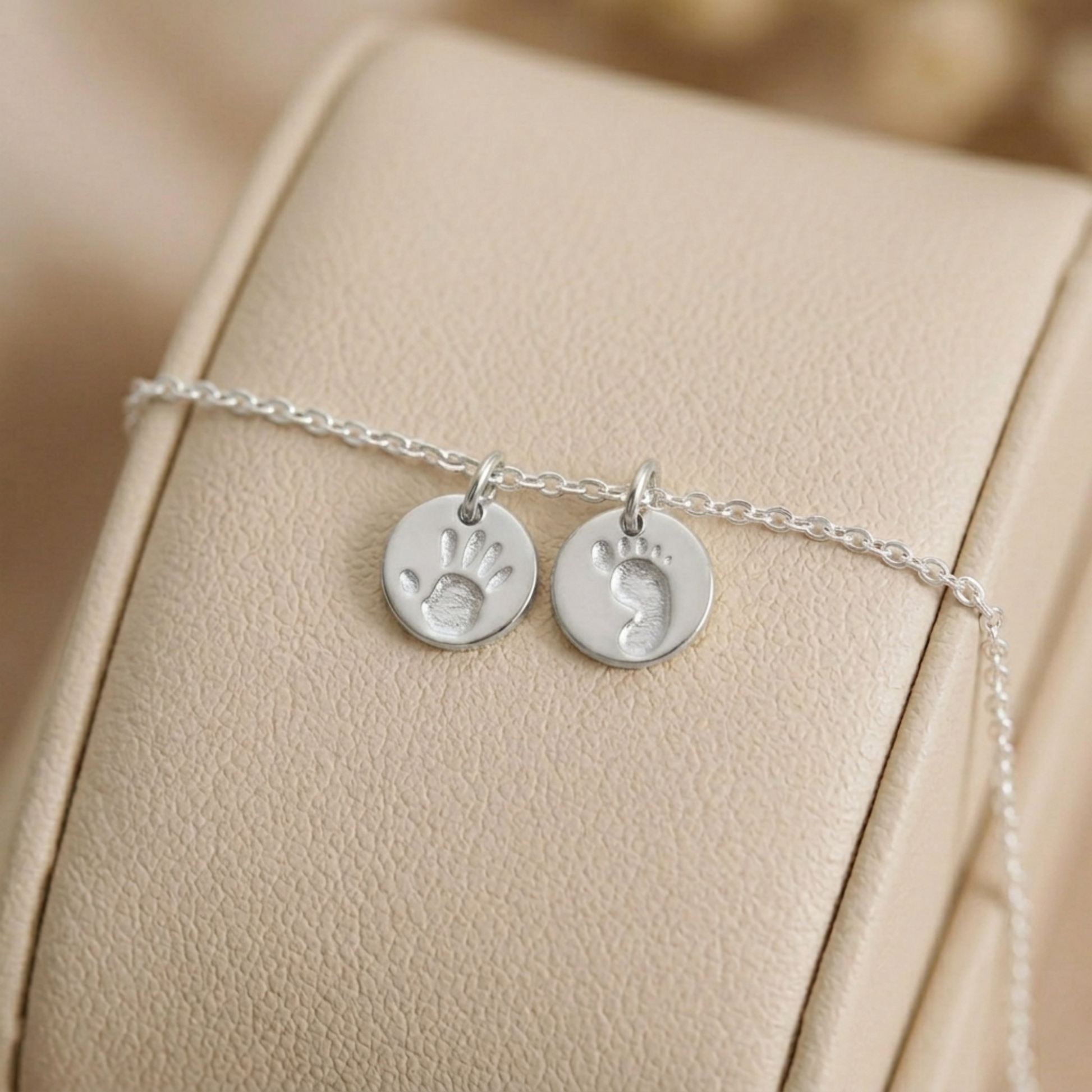 Silver round handprint and footprint charms on a thin chain