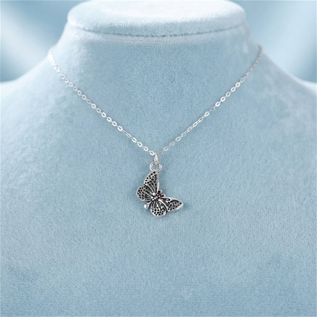 Silver butterfly charm pendant on a chain necklace with wing cutout details