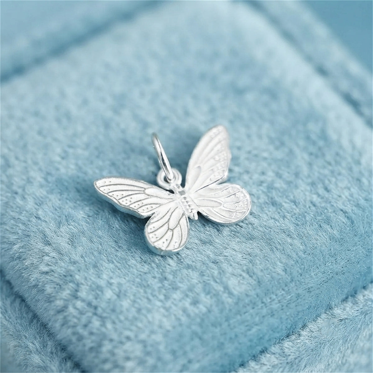 Silver butterfly charm pendant with textured wings and top loop bail