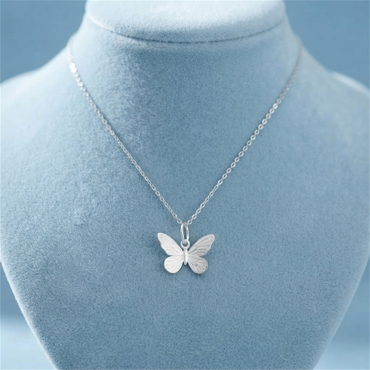 Silver butterfly charm pendant on a fine chain necklace with round loop bail