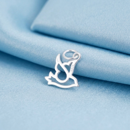 Silver dove peace charm with loop bail, resting on light blue fabric