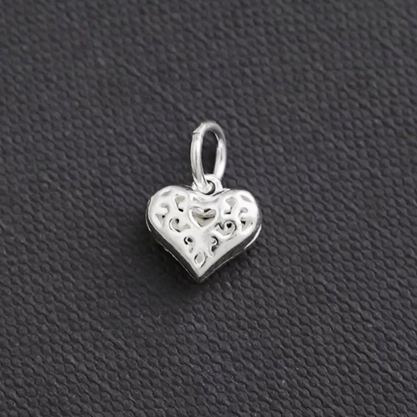 Hollow filigree heart charm pendant in silver tone, side view